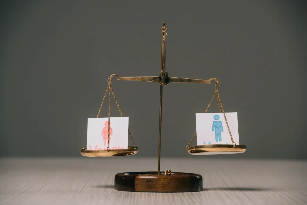 Scales of justice balancing cards with male and female symbols.