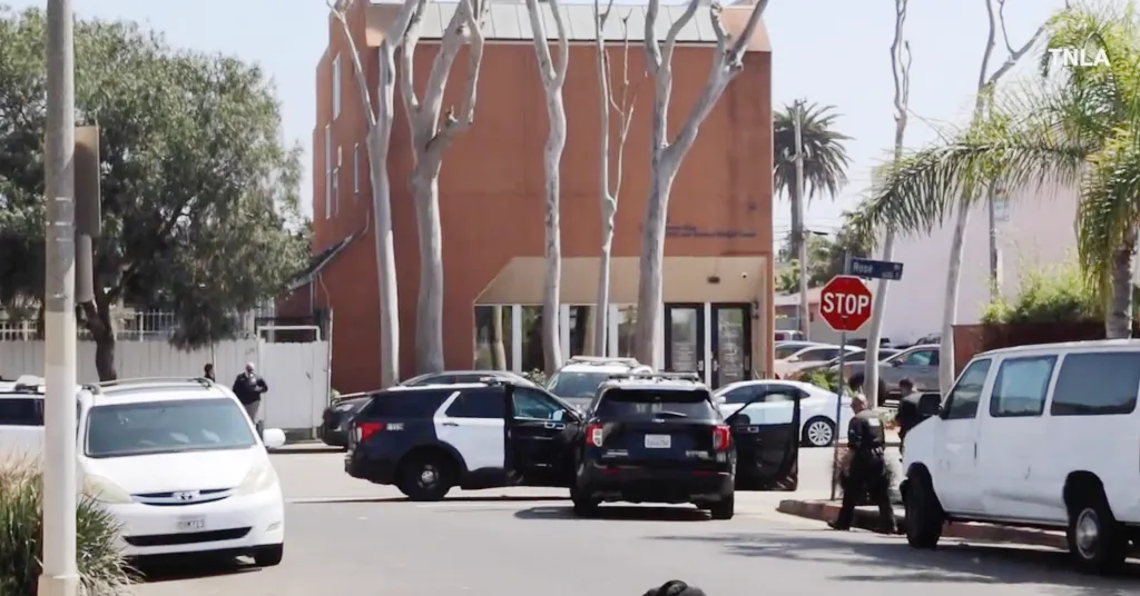 Police cars on Rose Avenue in front of a building with a stop sign visible.