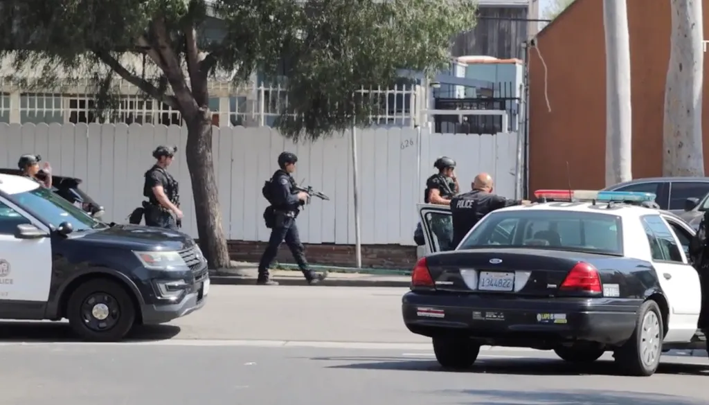 Police officers, one carrying a rifle, respond to a barricade situation.