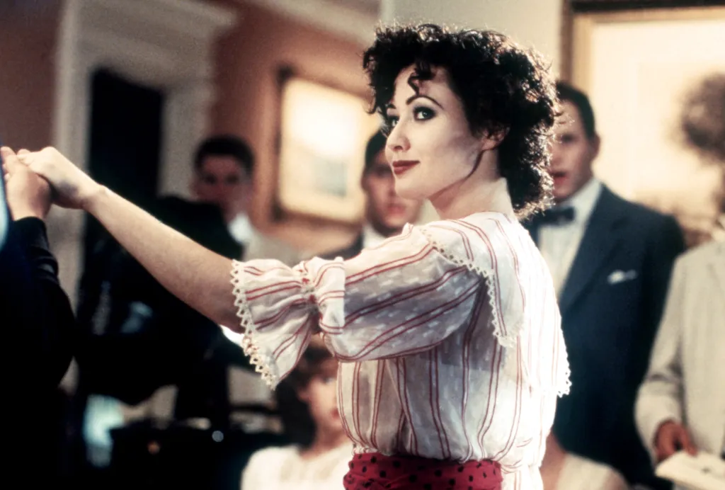 Shannen Doherty in a lace blouse, looking over her shoulder while dancing.
