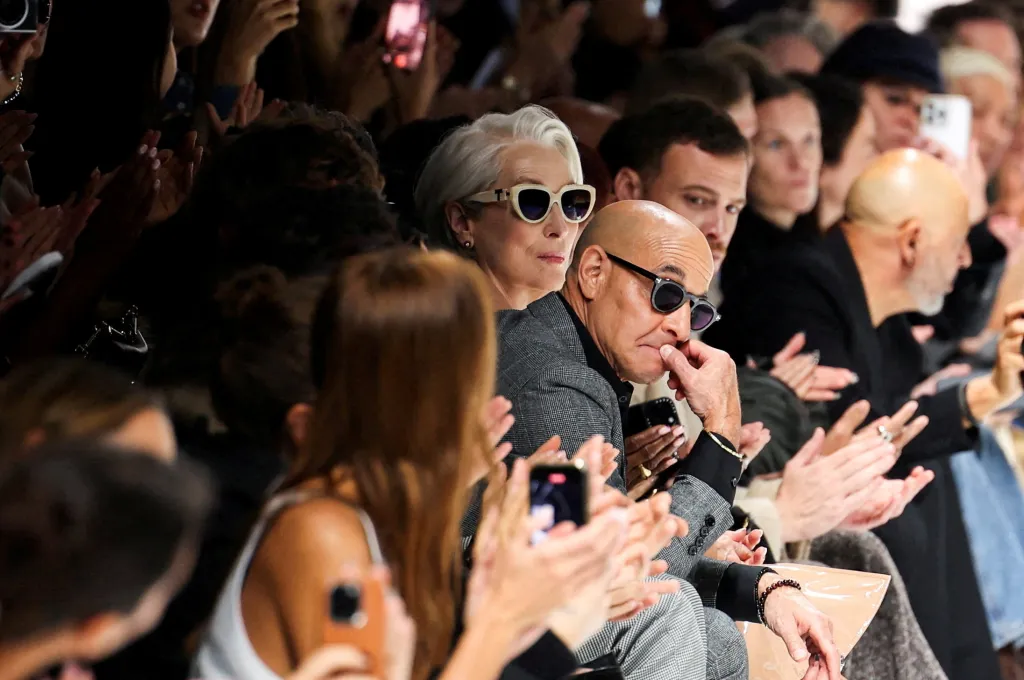 Meryl Streep, in sunglasses, and Stanley Tucci, in a grey jacket and sunglasses, watching the Dolce & Gabbana fashion show.