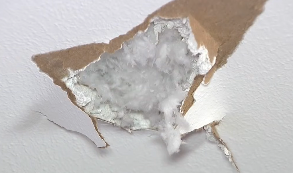 Torn plasterboard ceiling revealing insulation.