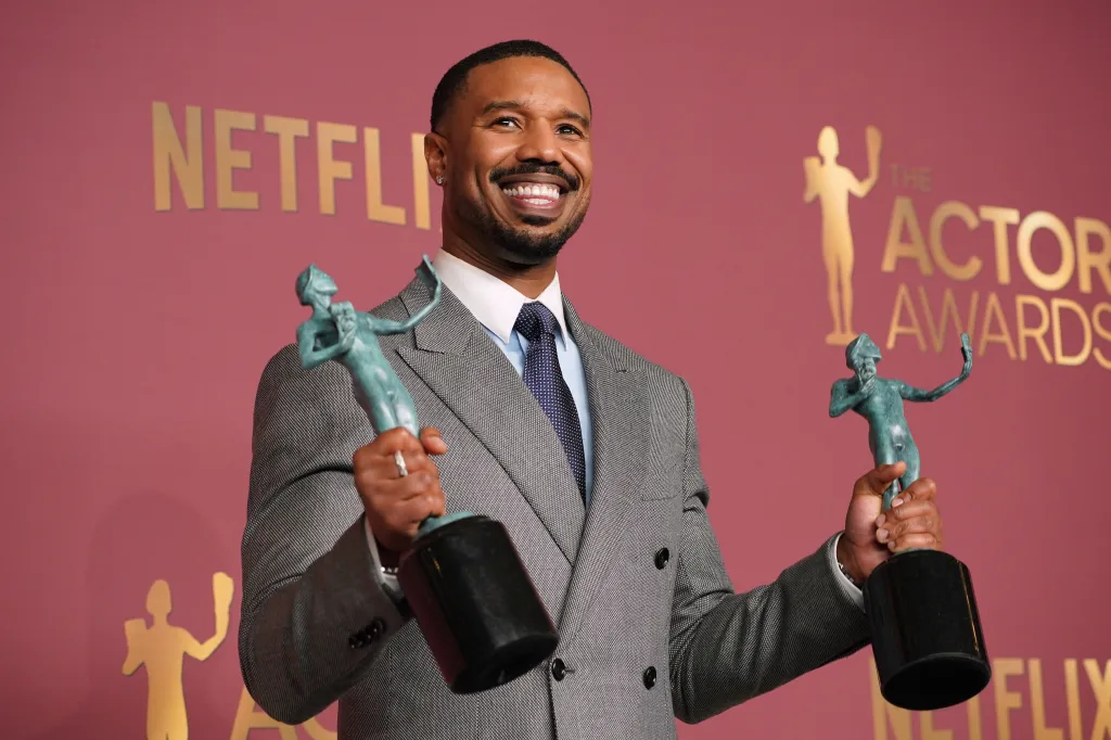 Michael B. Jordan smiles holding two SAG-AFTRA Actor awards.