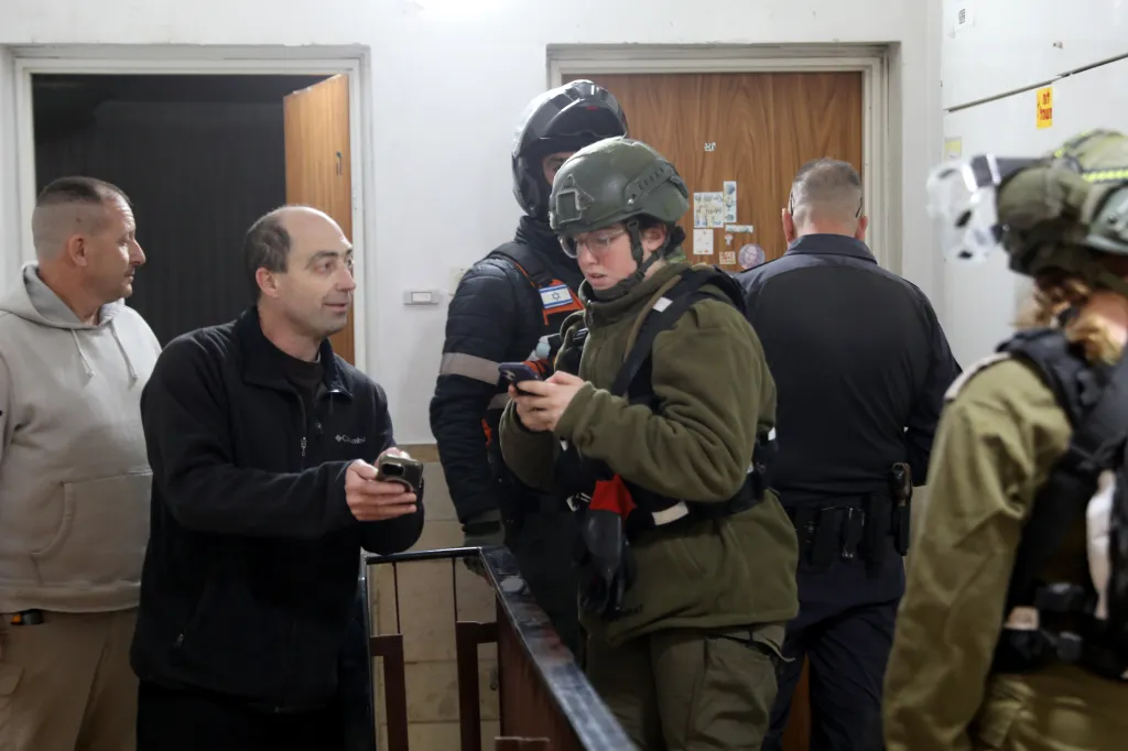Civilians and emergency services personnel assess damage from a missile strike in Tel Aviv.
