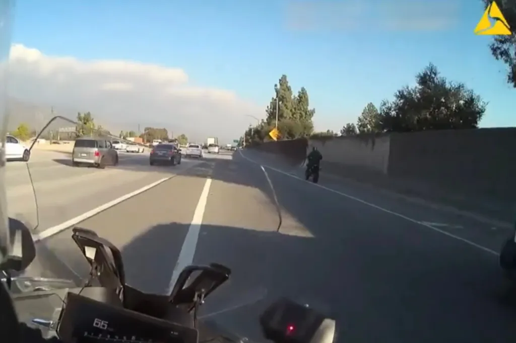 A view from a motorcycle of another motorcyclist ahead, weaving through traffic on a highway.