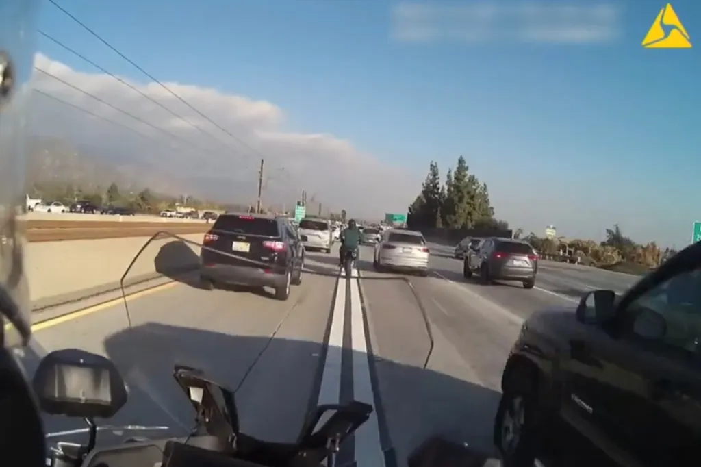 Motorcyclist evading police by weaving through traffic on a highway.