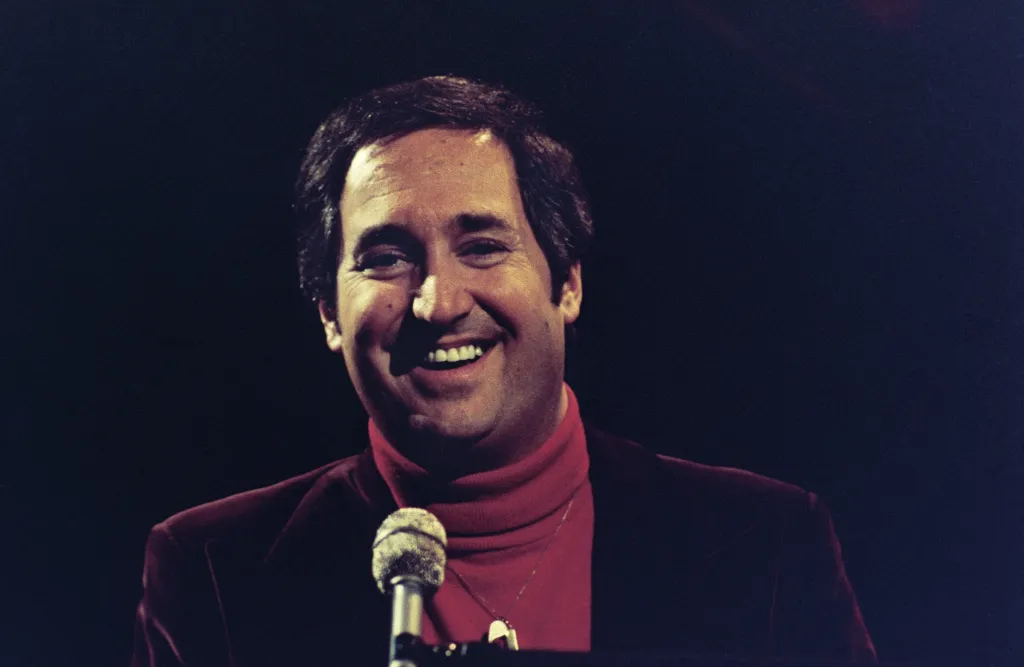 Musical guest Neil Sedaka smiling at a microphone on Saturday Night Live.