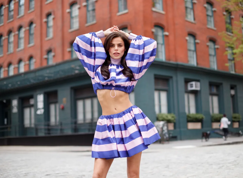 Model Brooks Nader posing in a purple and pink striped outfit in Tribeca.