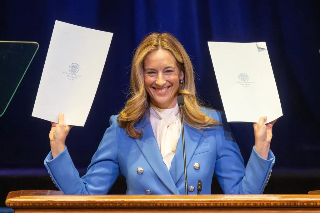 Governor Mikie Sherrill holds up two executive orders she just signed that lower utility prices.