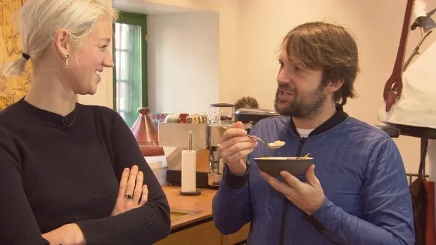 René Redzepi eating from a bowl as Nadine Redzepi watches him.