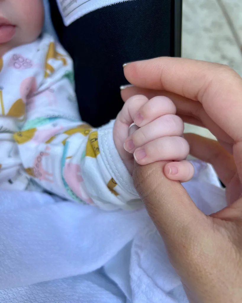 A close-up of a baby's hand clutching an adult's finger.