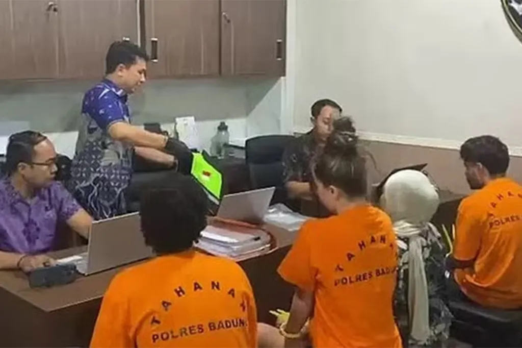 An OnlyFans star and two men, arrested after filming X-rated content in Bali, sit with officials.