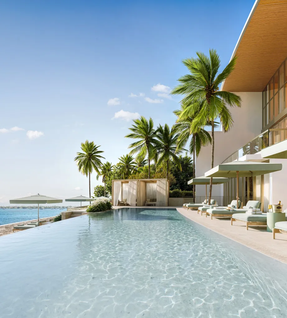 Rendering of an infinity pool overlooking the ocean, surrounded by palm trees and lounging areas.