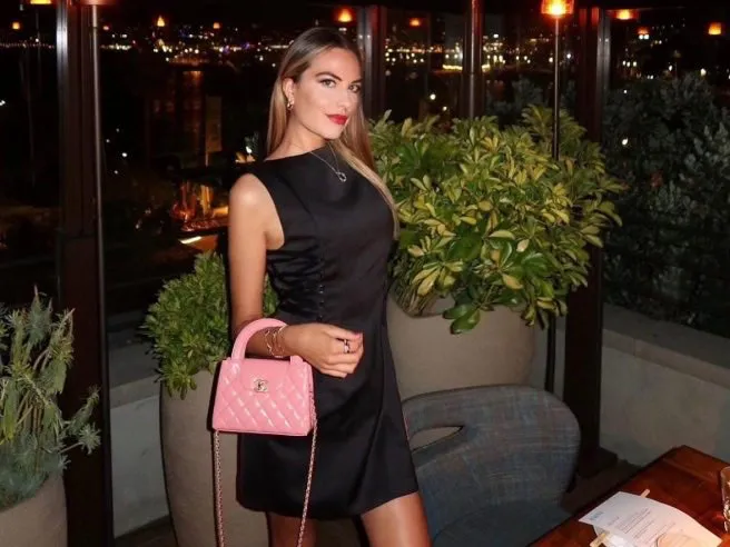 Model Pamela Genini poses with a pink Chanel purse at an outdoor restaurant at night.