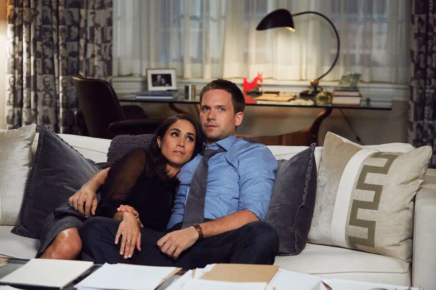Meghan Markle and Patrick J. Adams embracing on a couch, appearing as their 