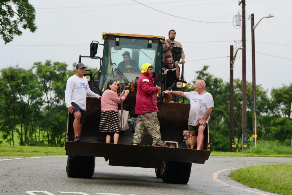 People being evacuated from Haleiwa, Hawaii, on a bulldozer during floods.