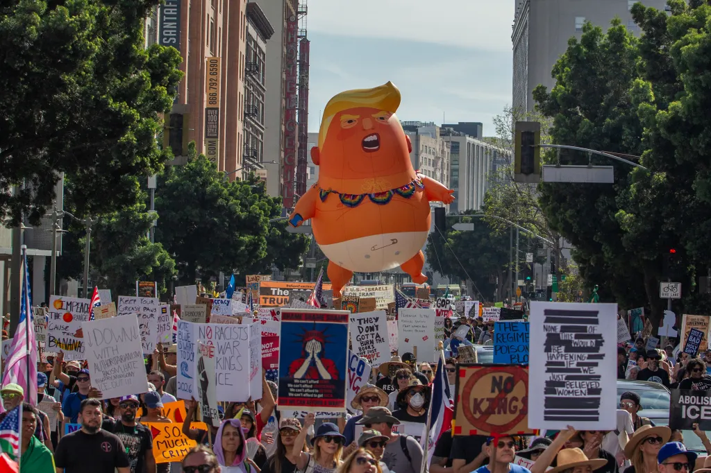 People protest immigration enforcement and federal overreach, featuring a large balloon of Trump in a diaper.