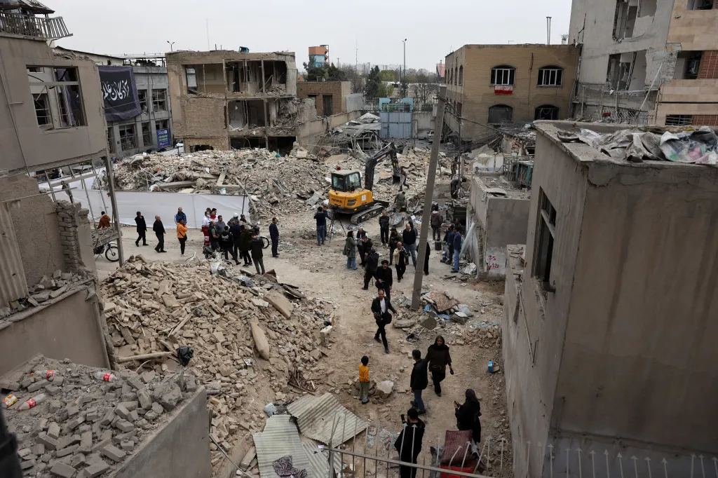 People walk through a street filled with rubble from damaged buildings in Tehran after a strike.