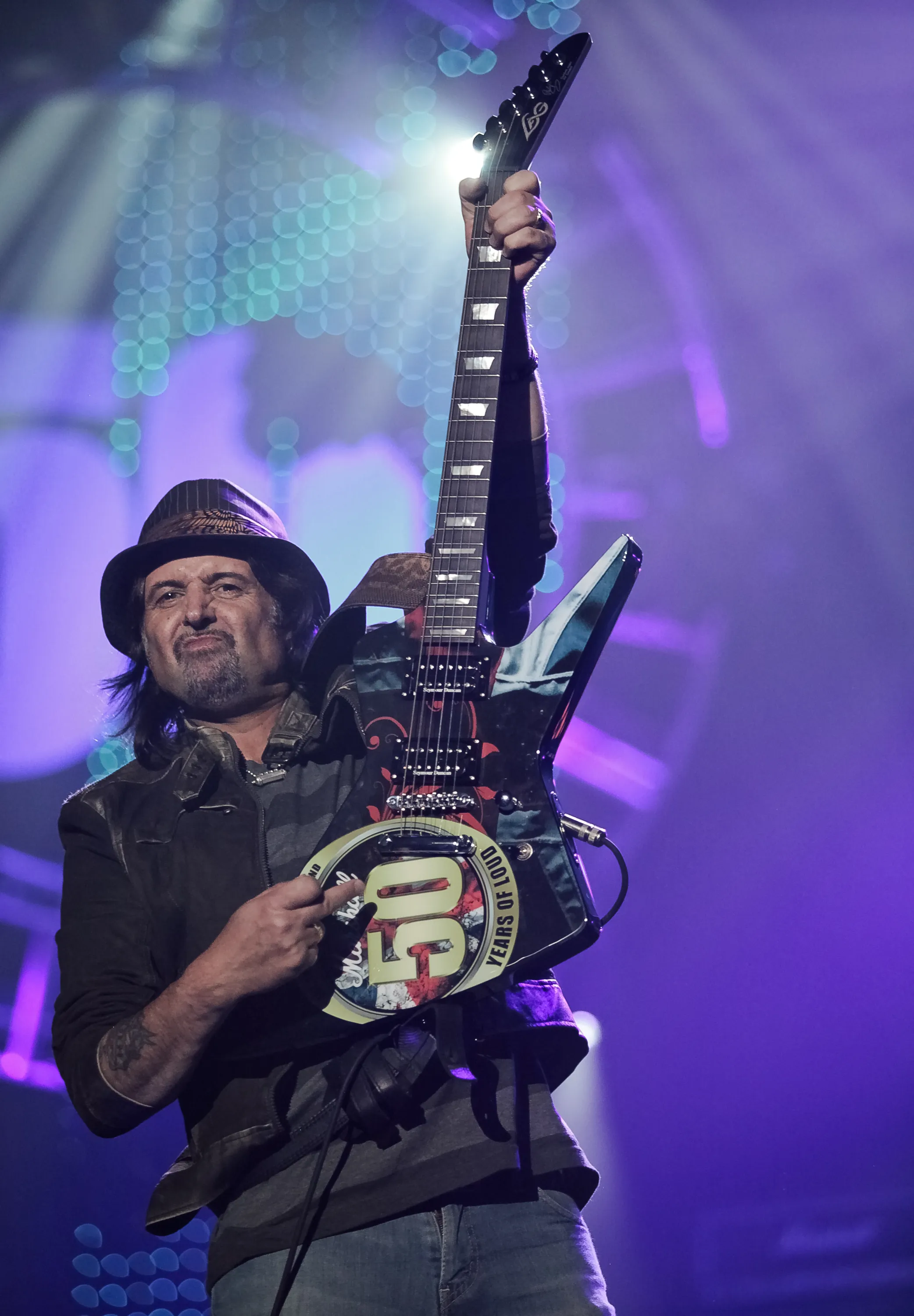 Phil Campbell of Motörhead performing on stage, holding his guitar upwards.