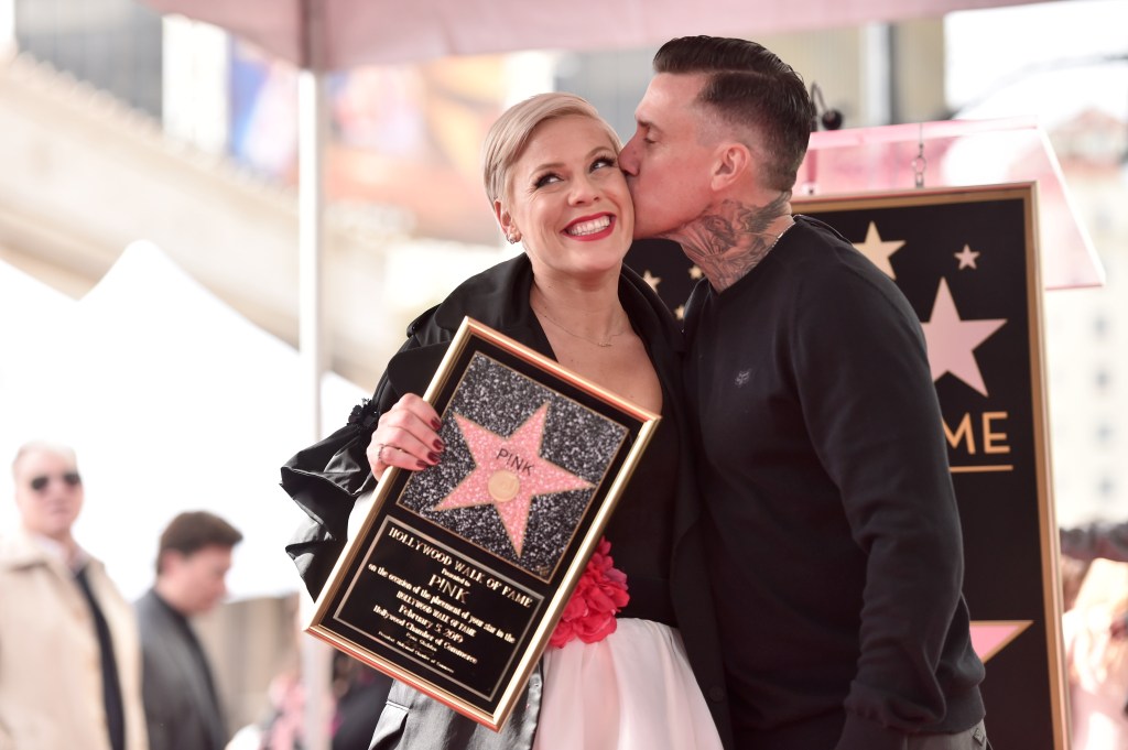Pink holding her Hollywood Walk of Fame star while Carey Hart kisses her cheek.