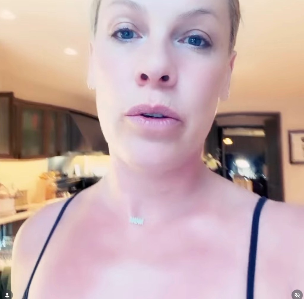 Pink speaking in a video, wearing a black tank top and a necklace.