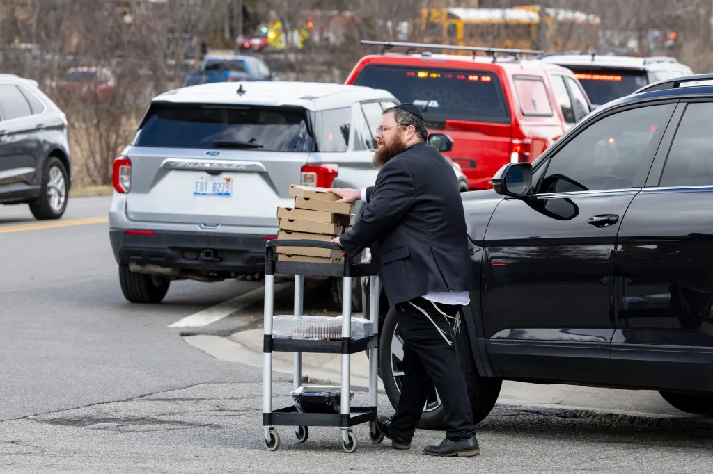 Man pushing a cart of pizzas and food at the scene of the Michigan synagogue attack.