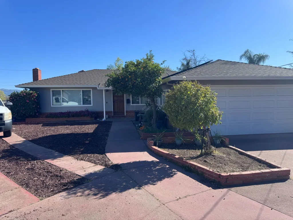 A single-story gray house with a brown front door and white garage door.