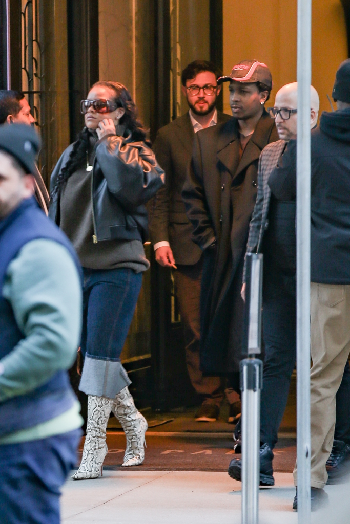 Rihanna and A$AP Rocky exiting a building, surrounded by bodyguards.
