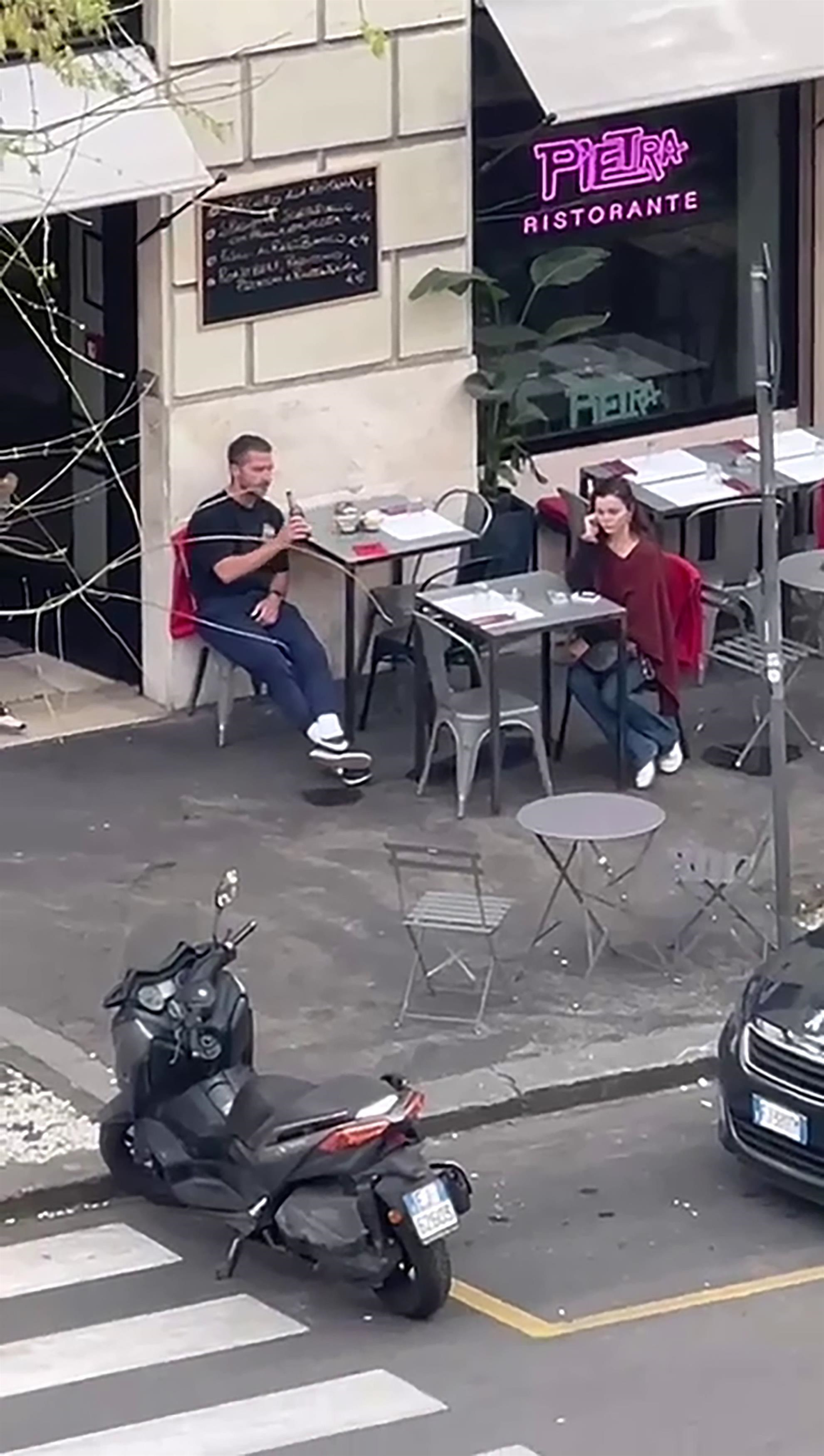 Shia LaBeouf seated outside Pietra Ristorante in Rome, involved in a tense exchange with a female companion.