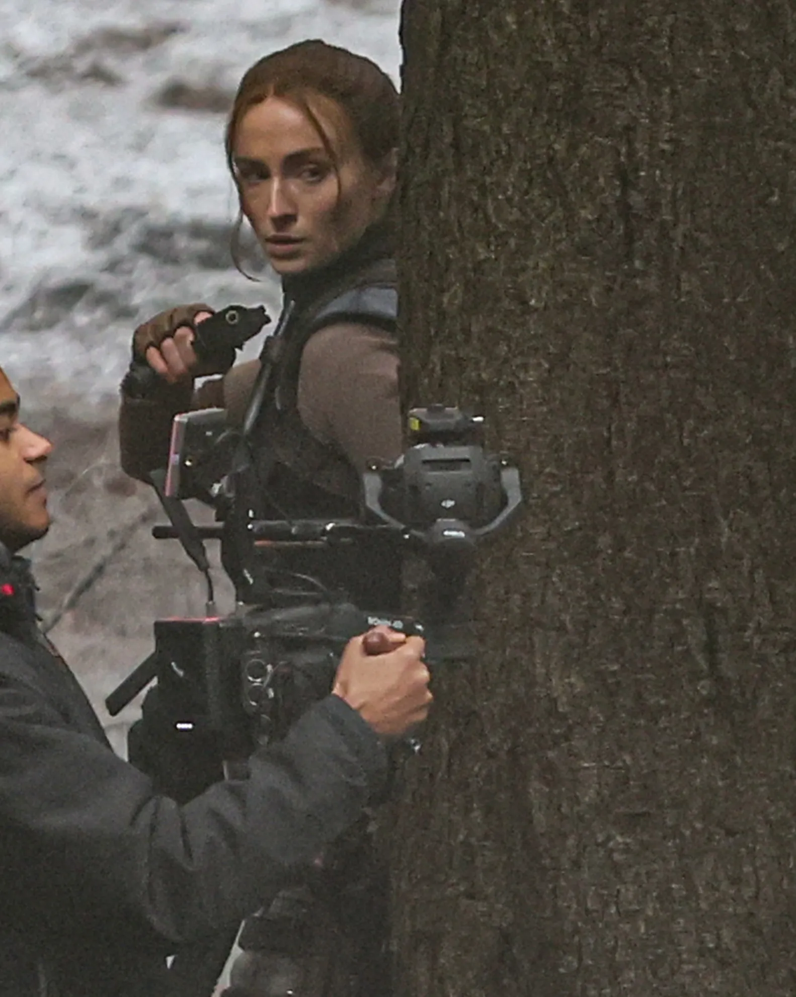 Sophie Turner as Lara Croft, wielding a pistol on the set of Tomb Raider.