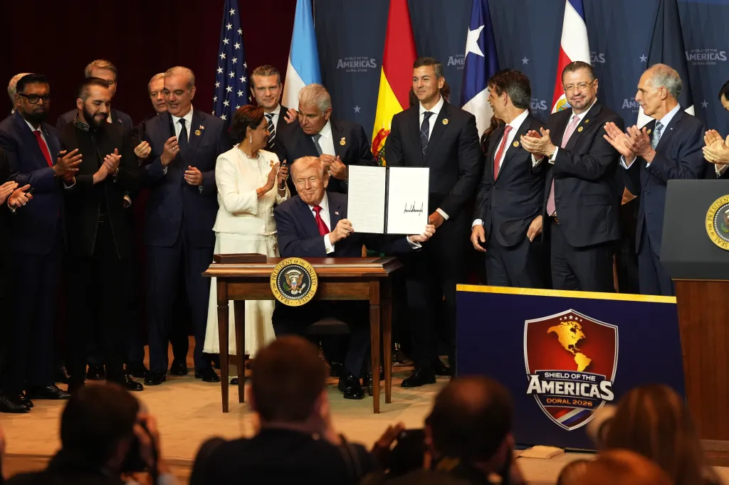 President Donald Trump holds up a newly-signed proclamation at the Shield of the Americas Summit.