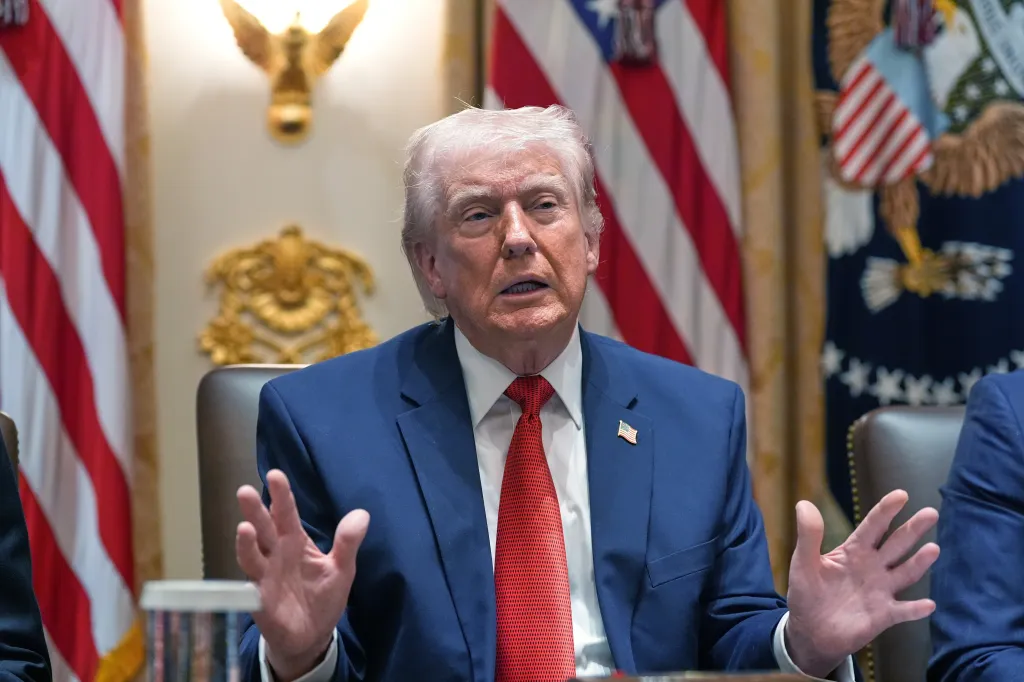 Donald Trump speaking during a Cabinet meeting with a US flag in the background.