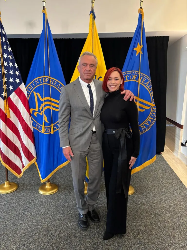 Pussycat Dolls star Jessica Sutta and Robert F. Kennedy Jr. pose together in front of American and Department of Health flags.