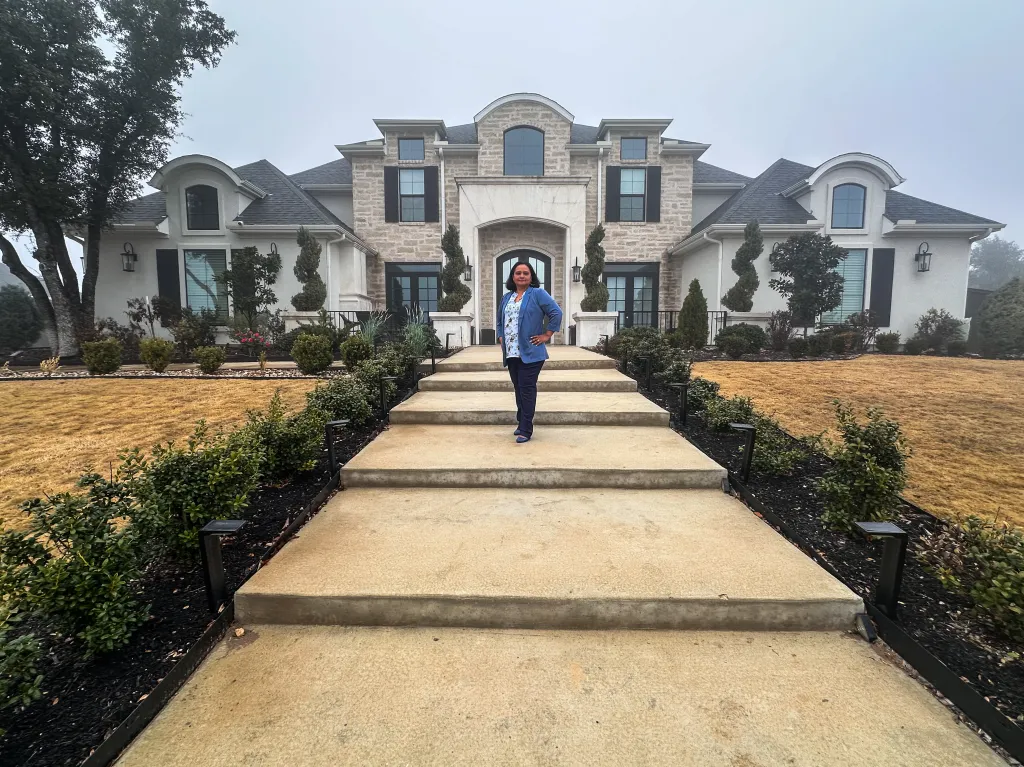 Jenny Wallace, a realtor, stands on the steps in front of her home in Texas.