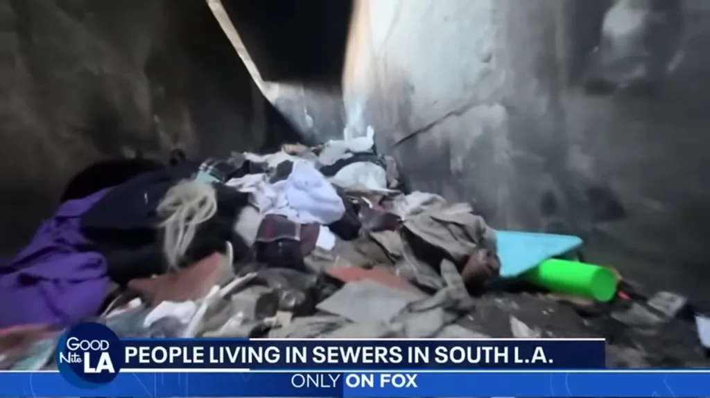 Rubbish and clothing piled in a dark sewer tunnel.