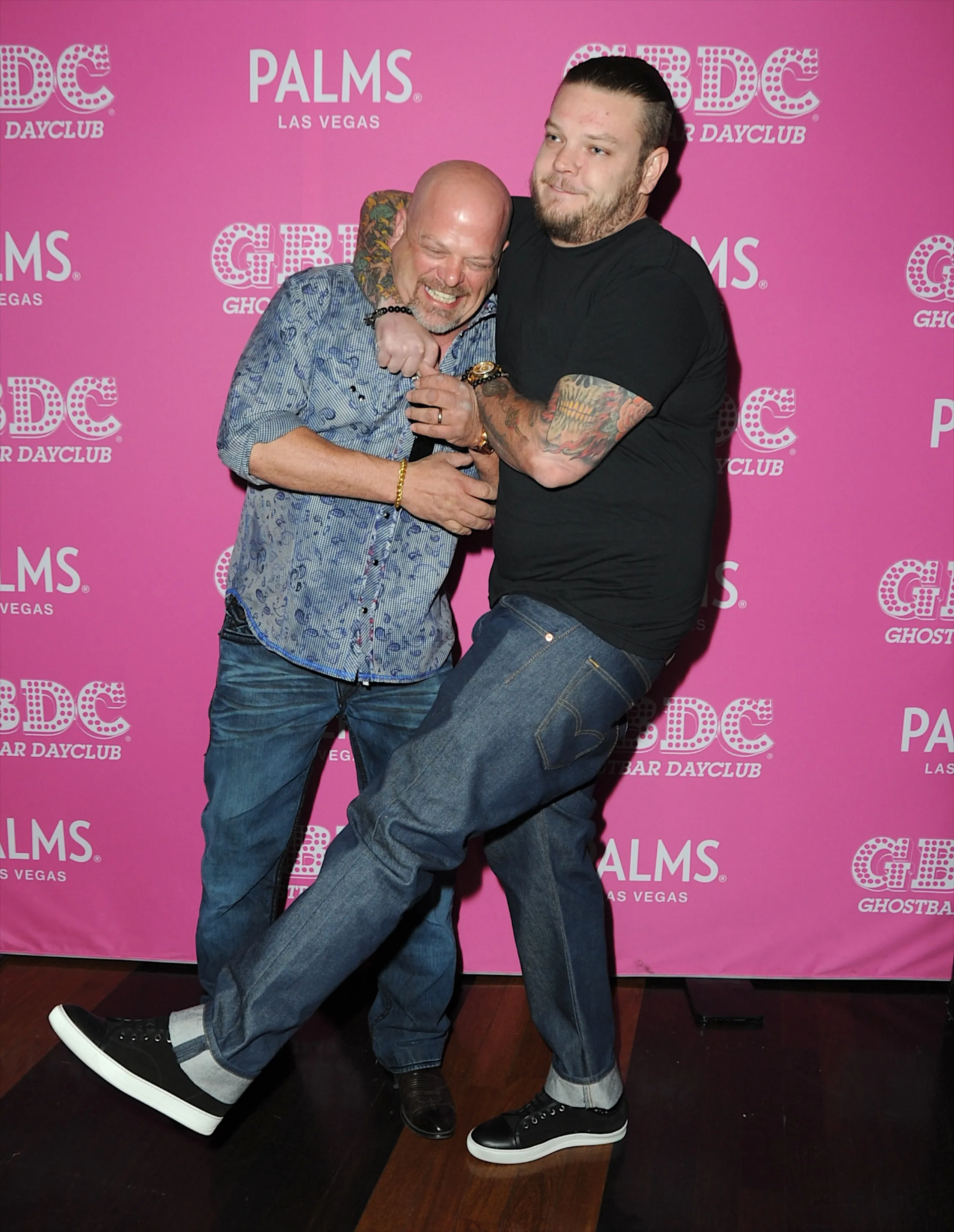 Rick Harrison and Corey Harrison pose together against a pink backdrop with the Palms Las Vegas logo.