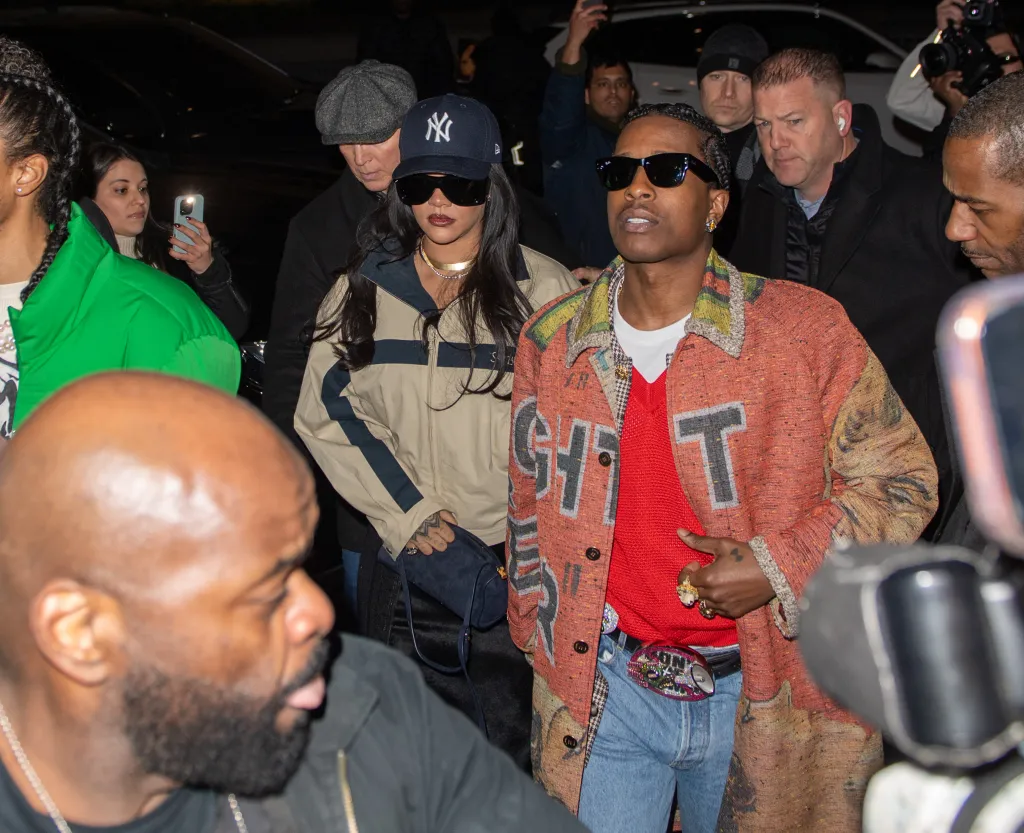 Rihanna and A$AP Rocky walking through a crowd at night.