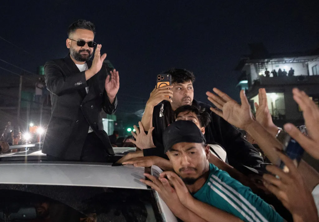 Rapper-turned-politician Balendra Shah celebrating his election win, waving to supporters from a car sunroof.