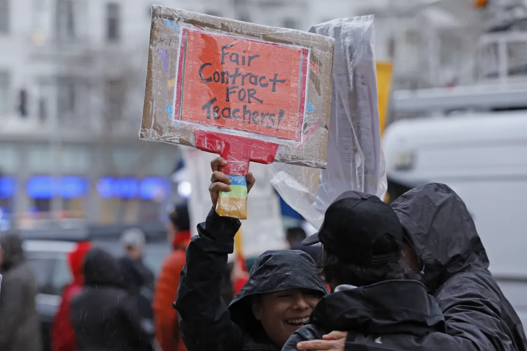 A protester in a black rain jacket holds up a 