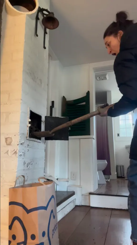 Sara Bareilles in an old country home, looking shocked as she shovels behind an unopened door.