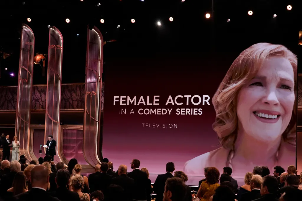 Seth Rogen accepts the award for Outstanding Performance by a Female Actor in a Comedy Series on behalf of Catherine O'Hara while Lisa Kudrow looks on.