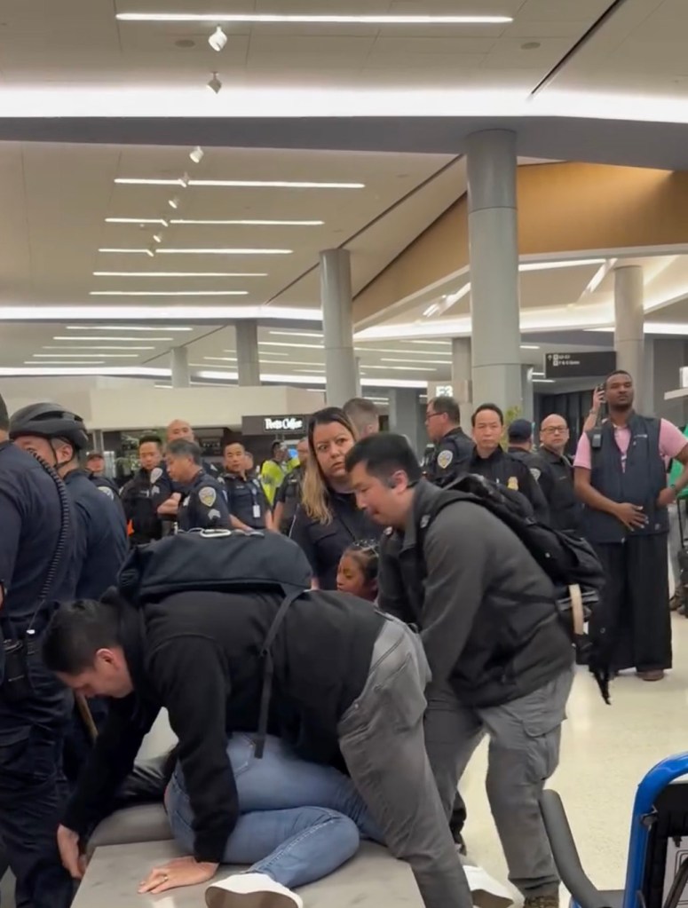 ICE officers detaining a woman with a young child at San Francisco International Airport.