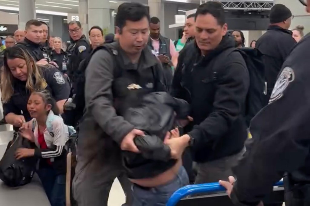 ICE officers detain a woman with a young child at San Francisco International Airport.