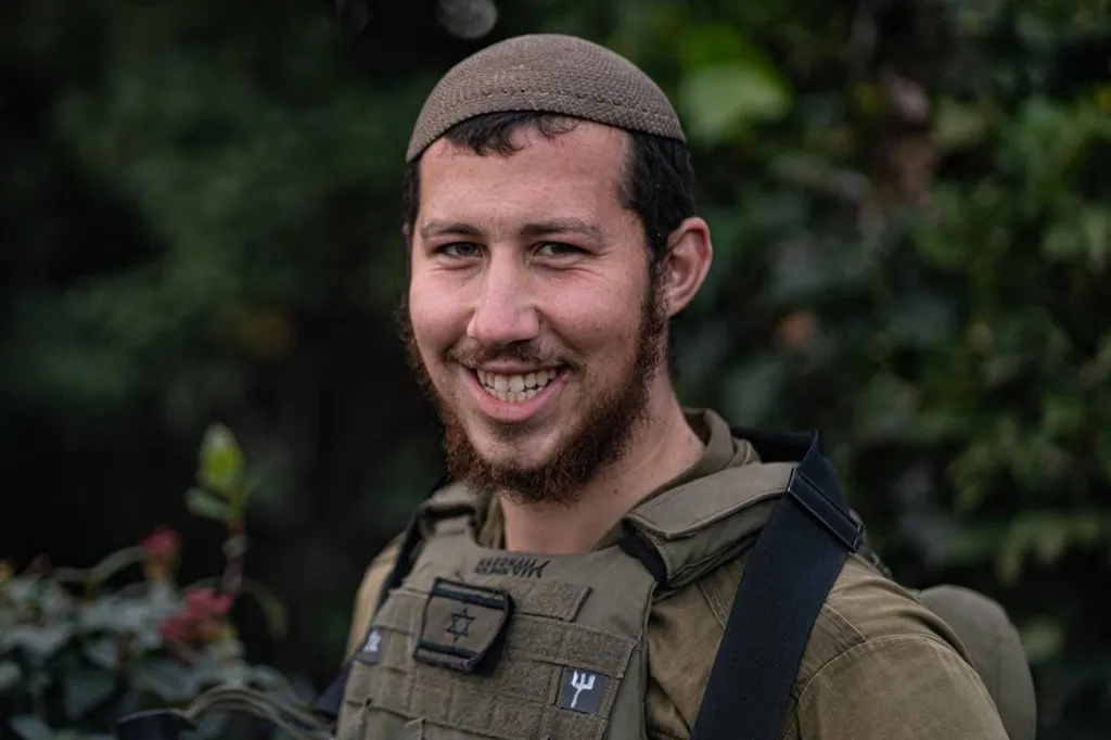 Sgt. Moshe Yitzchak Hacohen Katz smiling, wearing a kippah and tactical vest with an Israeli flag patch.
