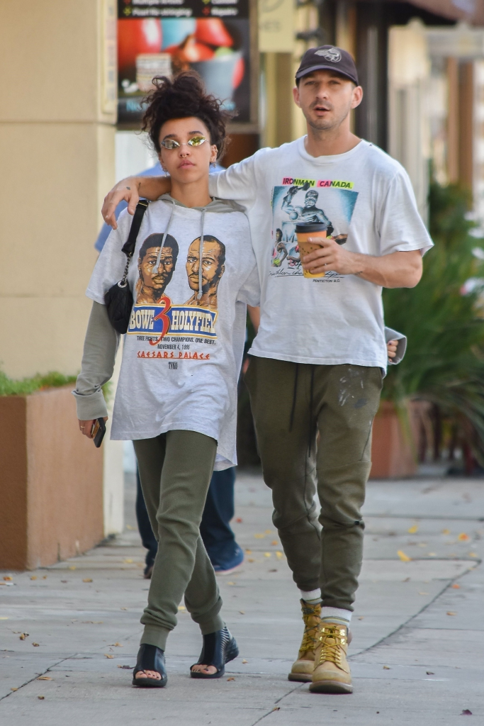 Shia LaBeouf with his arm around FKA Twigs as they walk down a sidewalk.