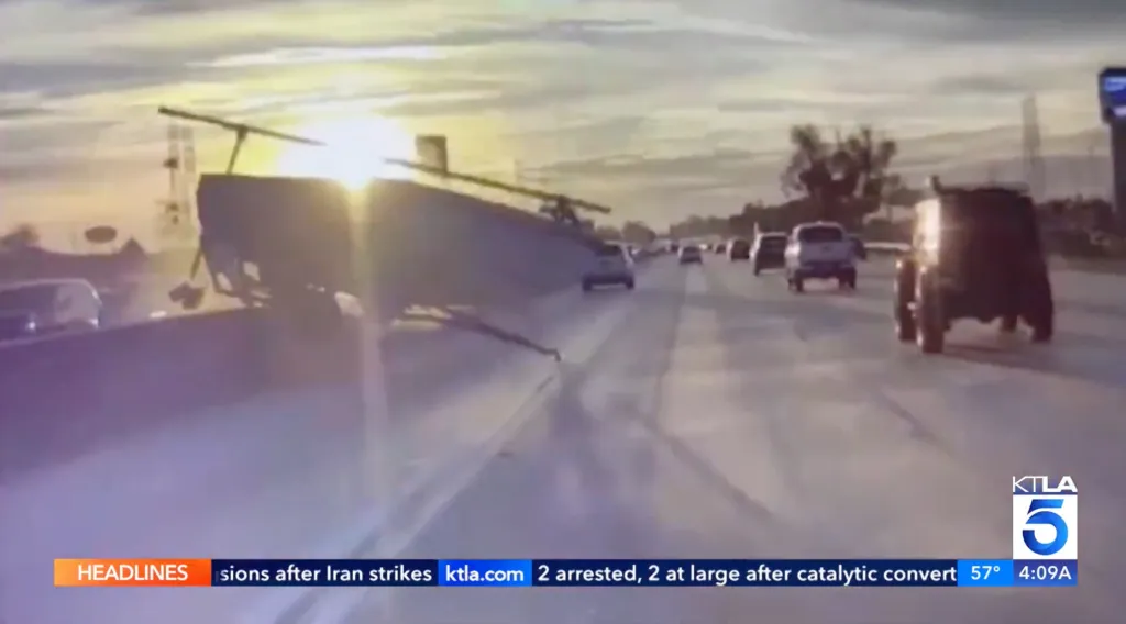A small boat on a trailer flies over the center median of a freeway, captured by a dashcam.