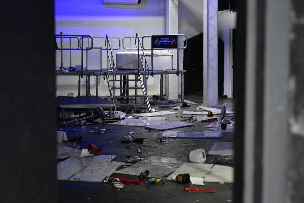 Debris scattered across a floor with event staging in the background.