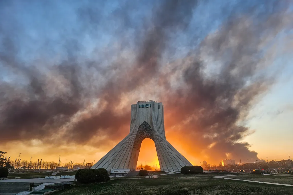 Smoke rises behind the Iranian tower of freedom in Tehran on March 3, 2026.