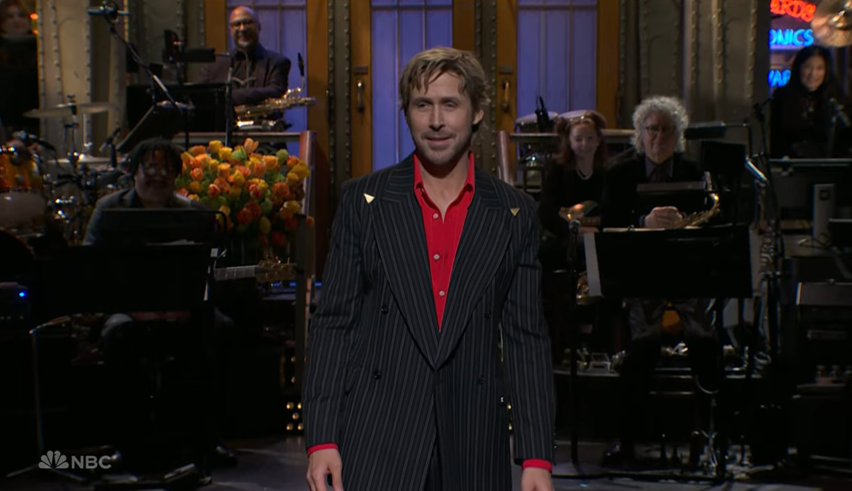 Ryan Gosling in a pinstriped suit jacket and red shirt on the set of Saturday Night Live.
