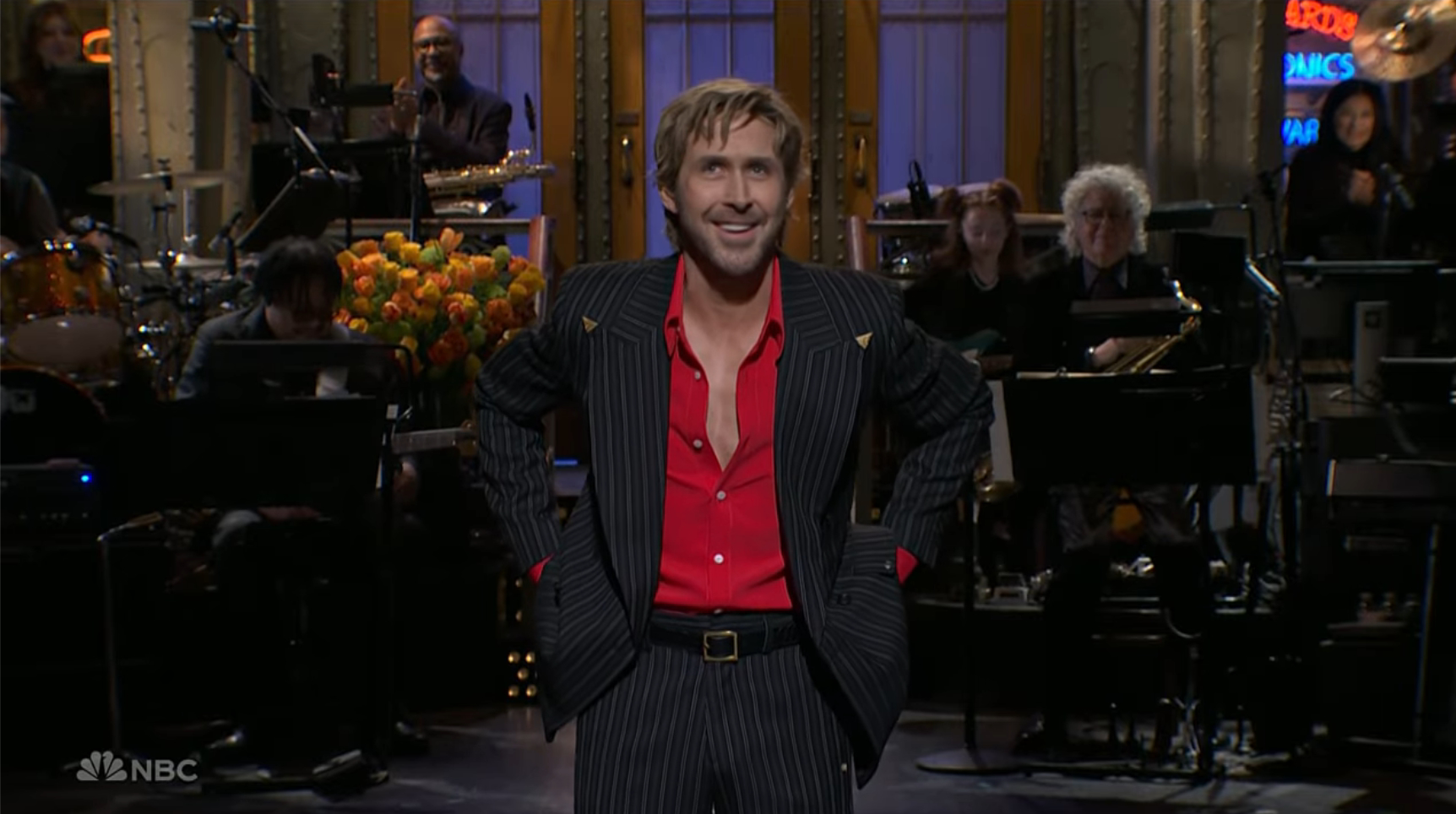 Ryan Gosling hosts SNL in a pinstriped suit and red shirt.